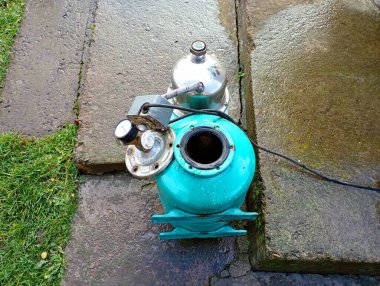 Beton bir yolda parçalanmış yeşil bir su pompası. Basınç altında su tedarik etmek için ekipman onarımı.