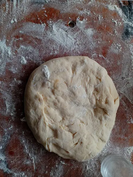 Kneaded dough for pies on a wooden board. Cooking food from wheat flour. The topic of baking and kneading bread.