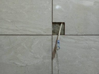 Duvar beyaz seramik fayanslarla kaplı. Duvardan bir elektrik kablosu çıkıyor ve bir elektrik prizi için tasarlanıyor..