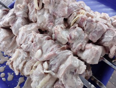 Terbiye edilmiş eti şişin üzerine koy ve ateşte pişirmek için bir yığın içine koy..