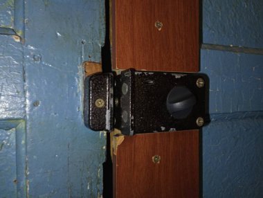 Kapı, ortadan kapanan eski mavi bir kapıya kilitlenir. Siyah kapı kilidi.