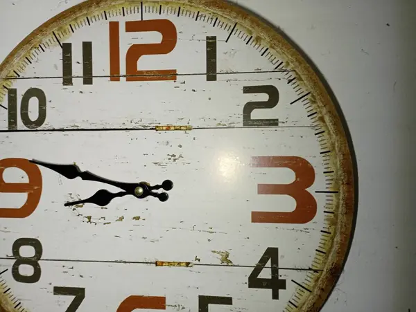 The dial of an old mechanical clock made of wood. Old mechanical wall clock with numbers and two hands showing hours and minutes.