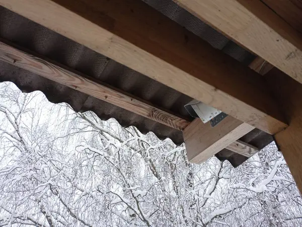 The video surveillance camera is hidden on the veranda under the roof and attached to a wooden beam. The base of the roof on which the security video surveillance system is mounted.