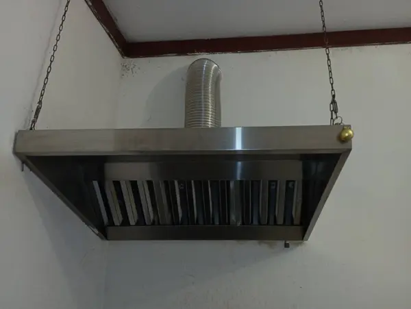 A professional kitchen hood made of stainless steel that is installed above the surface of the cooking surface. Kitchen equipment and items.