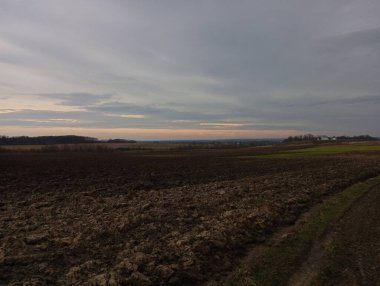 Gün batımında akşam manzarası. Güneş ufukta batar ve gökyüzünü parlak kırmızı ışıkla aydınlatır. Doğa ve tarım arazisi