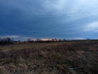 Kuru otlarla dolu tarlaların üzerinde sabah güneşi doğuyor. Bahar tarlalarının üzerinde parlak mavi gökyüzü. Güneş ufukta beliriyor ve etrafındaki her şeyi ışınlarıyla aydınlatıyor..