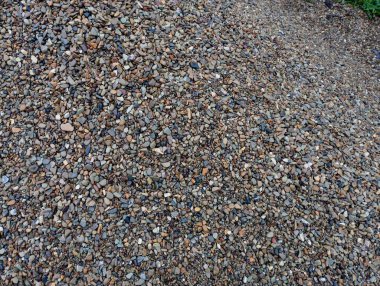 Bir yığın içine farklı renkte küçük taşların dokusu döküldü. Bir sürü küçük gri nehir taşları kumdan süzüldü..