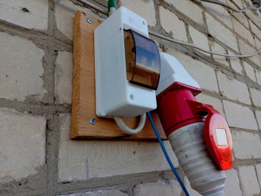 Tuğla bir evin duvarında kendi kendine çalışan bir araba. Elektrik yükleme, elektrik paketlerinin sigortalandığı bir duvardır..