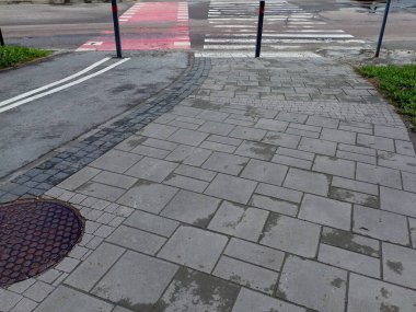 Karşıdan karşıya geçen bir yaya ve bisiklet var. Bisiklet yolu ve kaldırım köşeden karşıya geçiyor. Ulaşım yollarının kesiştiği yer. Yayalar ve araçlarla kesişen bisiklet taşımacılığı için altyapı ekipmanları.