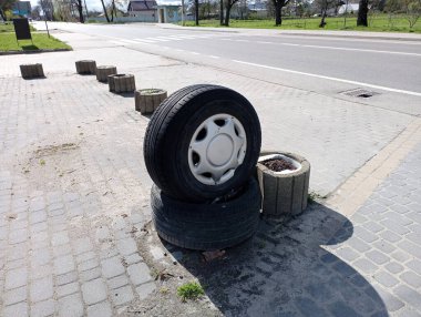 Tekerlekler yolun kenarında yatıyor. Yolun yanındaki kaldırımda tekerlekler var..
