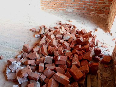 Bir dağ dolusu kırık tuğla bitmemiş bir evin binasına atıldı. Kırmızı kil tuğlalardan konut binaları inşa ediliyor.