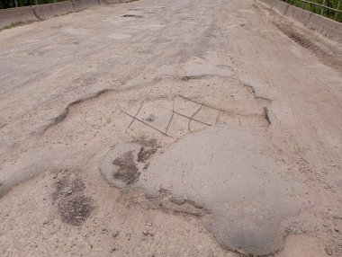 Nehrin üzerindeki köprüde harabe yol yüzeyi. Yolda büyük çukurlar var. Trafik için kötü yol ve yetersiz yol yüzeyi.