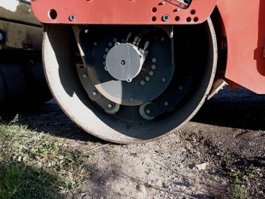 Turuncu bir pistin büyük metal tekerleği. Yol onarım ve araç gereç konuları. Otomotiv, yolları onarma aracı.