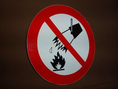 Açık ateşe su dökmenin yasaklandığına dair yuvarlak bir yasaklama işareti. Beyaz dairesel arka plandaki ateş yasağı tabelası kırmızı bir çizgi ile çizilmiştir. Kırmızı bir kovadan su dökülüyordur..