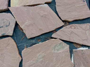 Görsel örnek ve inşaat malzemesi reklamı için siyah bir duvar yüzeyine kırmızı kumtaşı serilmişti. Kırmızı yapının arka planı doğal taş.