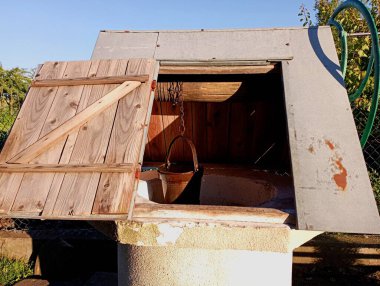 Köyde kapısı açık bir kuyu ve su toplamak için bir kova. Suyu olan eski bir köy. Beton halkalardan yapılmış bir çatı ve metal bir levhayla kaplı..