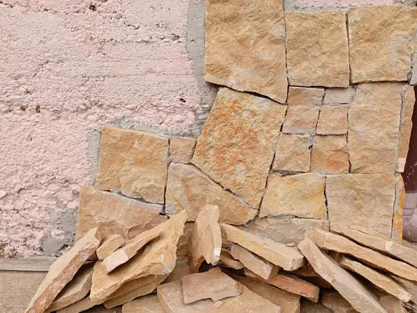 stock image The concrete wall is covered with a special primer and part of the ground is faced with stone. Wall cladding with natural materials.