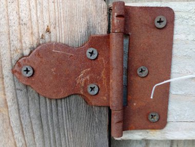 Tahta kapıya vidayla tutturulmuş paslı metal perde..