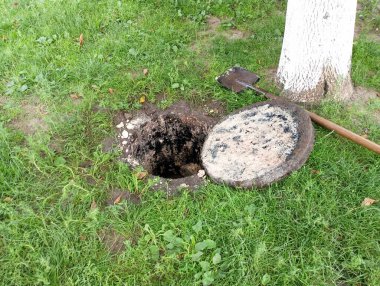 Yeşil çimenler ve süngü kürek üzerinde beton rögar kapağı açıldı..