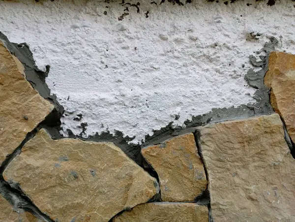 stock image The process of repairing and facing the facade of the concrete wall of the house with natural river torn stone and sandstone.