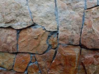 Beton bir duvarın süslendiği kahverengi kumtaşından bir zemin. Doğal malzemelerin arka planı.