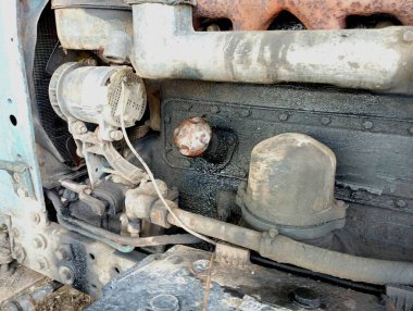 The background of the engine compartment of an old tractor with engine oil. Dirty old engine of agricultural machinery. Black dirty tractor engine.