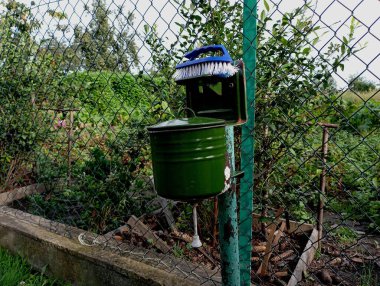 Bahçedeki eski yeşil metal bir leğen metal bir direğe asılı..