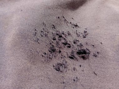 Yırtık siyah sentetik kumaşın arka planı. Kara kumaşa sürtünmüş delikler.