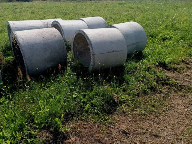 Yeşil çimenlikteki bir kuyu için beton halkalar. Kuyunun duvarlarını bitirmek için özel beton halkalar..