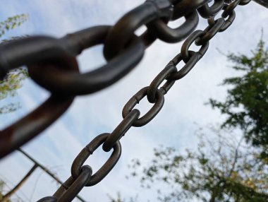 Mavi gökyüzü zeminine karşı gerilmiş güçlü metal bir zincir..
