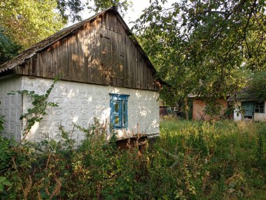 Köyde beyaz bir duvarda mavi penceresi olan eski bir ev. Eski köy mimarisi. Eski, rahat bir evi olan kırsal manzaralar..