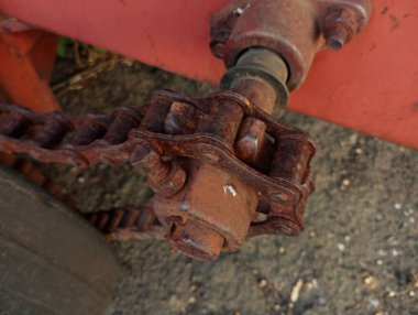 Kalın bir makine zinciri, zirai makinelerde torku iletmek için bir çıkıntıya gerilir. Kalın metal, paslı, eski zincir..