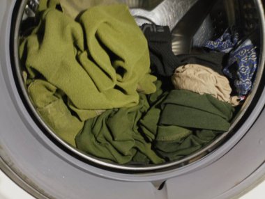 Çamaşır makinesinin açık kapağı varilin içinde. Ev ödevi ve giysi bakımı konusu. Çamaşır yıkıyorum..