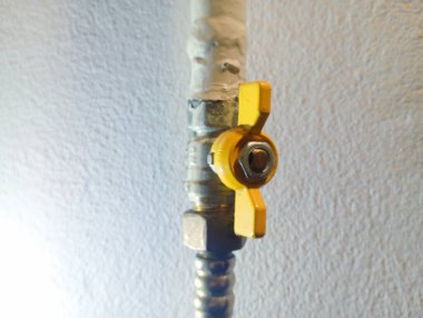 Borulardan gaz akışını kesmek için sarı musluk. Duvardaki gaz borusunda sarı bir musluk var..