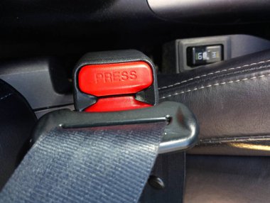 Yolcu ve sürücülerin yaralanmasını önlemek için emniyet kemeri takılmış. Tokalı arabada geniş siyah bir emniyet kemeri..