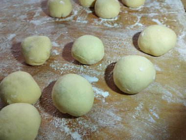 Mutfak tahtasının ahşap yüzeyinde çörekler kızartılmaya ve un serpilmeye hazırdır..