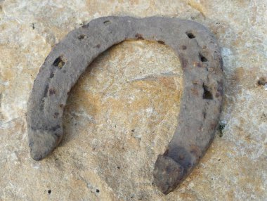 Kahverengi kumtaşı arkaplanındaki paslı at nalı. Bir buluş ve bir şans ve mutluluk işareti..