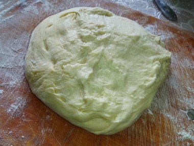 Mutfaktaki tahta bir tahtanın üzerinde yoğurulmuş beyaz undan yapılmış hamur parçası. Un ile yemek pişirmek.