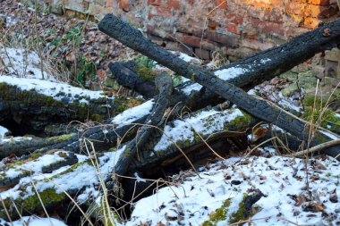 Fotoğrafta karla kaplı yanmış kirişler görülüyor. Ahşap siyah, kömürleşmiş. Kar bembeyaz, kirişlerin üzerinde yatıyor. Arka planda bir tuğla duvar yıkıldı. Fotoğrafta yıkım kavramı anlatılıyor..