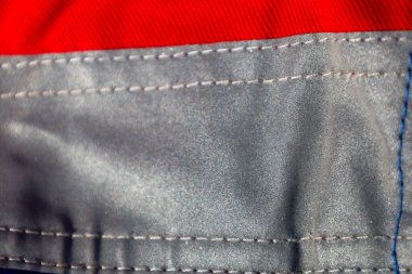 Fotoğrafta iki farklı doku ve renge sahip bir kumaş parçasının yakın çekimi var. Kumaşın üst kısmı küçük yatay çizgili parlak kırmızı bir renge sahiptir..