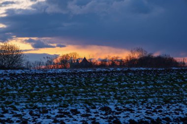 Kış akşamının büyüleyici bir manzarası. İlk karla kaplı bir alan ufka kadar uzanıyor, bir kilisenin siluetinin alacakaranlık gökyüzüne karşı görülebildiği yere..