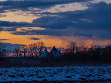 Canlı bir günbatımına karşı kilisenin siluetiyle büyüleyici bir kış manzarası.. 