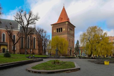 Drogobitch, Ukrayna, - 25 Mart 2025: Kompozisyonun ortasında, kırmızı çatılı tuğla bir kule dikey aksan ekleyerek ayakta duruyor.