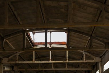Stock fotoğraf tanımı: harap olmuş beton bir binanın çatısının içerisinden görüntü. Beton levhalar, metal kirişler ve çatıda parlak gökyüzünün görülebileceği bir açıklık..