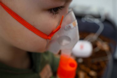 Bulanık arka planda bir nebulizör ve diğer tıbbi cihazlar görülebilir. Solunum terapisi, çocuklarda solunum hastalıklarının tedavisi
