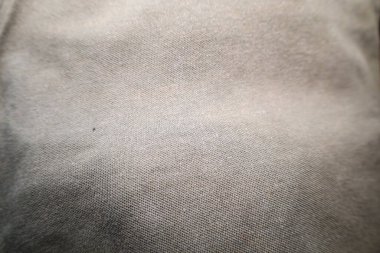 Açık gri kumaş dokusunun ince çapraz dokumasına yakın çekim. Bireysel iplikler ve hafif yüzey düzensizlikleri görülebilir. Yumuşak, sessiz ton.