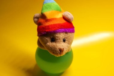 Kahverengi kürklü ve küçük yuvarlak kulaklı sevimli bir oyuncak fare parlak bir gökkuşağı şapkası takıyor. Şapka mavi, yeşil, sarı, turuncu ve kırmızı çizgilerden oluşur..