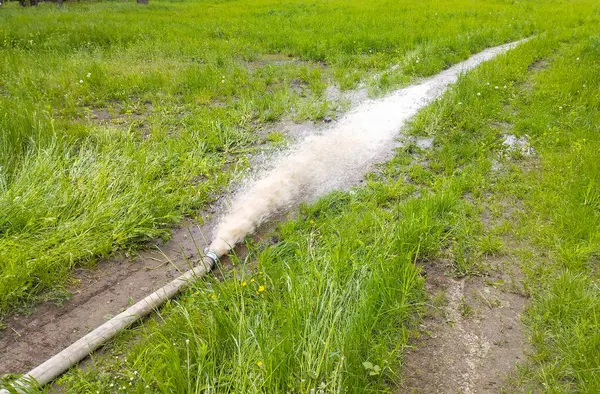 İnsanlar kazılardan kirli köpüklü su pompalamak için hortum kullanıyorlar. Kirli bir bölgeyi sıvıdan temizleme süreci endüstriyel aktivitenin gözle görülür sonuçlarıyla.