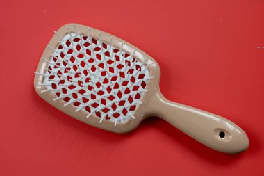 Zarif bir masaj fırçası, parlak kırmızı arka planda eşsiz bir delik. Tüm saç tiplerinin hassas çözülmesi için idealdir, rahat bakım sağlar..