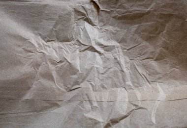 Kırışık ve eşitsizlikle buruşmuş açık kahverengi kraft kağıdı. Bu doku yeniden kullanımı sembolize eden arkaplan, ambalaj veya kavramsal projeler için idealdir..